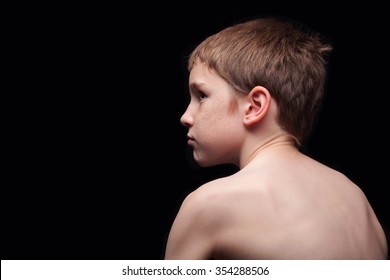 Low Lit Shot Of A Unhappy Shirtless Boy Looking To His Left At Copy Space