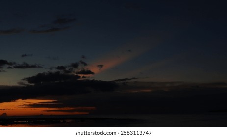 Low orange sunset in dramatic clouds over ocean in Indonesia