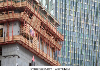 Low perspective on an elevator shaft under construction, with plywood concrete forms, and an office building in the background