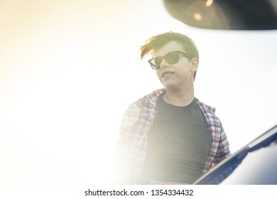 Low Perspective Portrait View Of A Joyful Teenager Feeling Happy And Smiling Against A Sunny Sky Background. Outdoors Healthy Lifestyle. Portrait Of An Handsome Young Man With Black Sunglasses