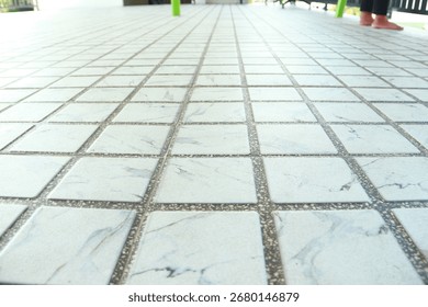 Low perspective view of a white marble patterned ceramic tile floor with gray grout.