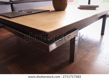 Low rectangular wooden coffee table with metal legs in a cozy living room, decorated with a yellow plant pot and books, ideal for illustrating home interior and living room decor and furniture.