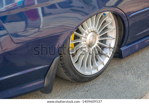 Low rider car tuning. Closeup on the wheel\
with lowered arch and colored braking system. Car and automibile\
industry background.