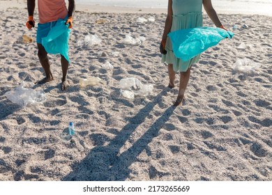 Low section of african american couple picking plastic waste on sand at beach. Unaltered, litter, pollution, recycle, responsibility and environmental issues concept. - Powered by Shutterstock