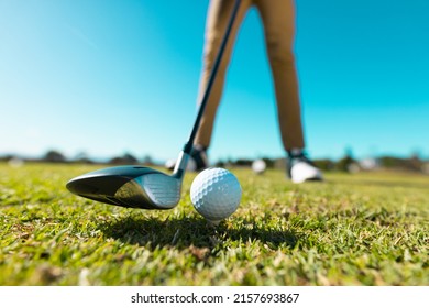 Low section of african american young man aiming ball with club at golf course against clear sky. copy space, summer, golf, unaltered, sport and weekend activities concept. - Powered by Shutterstock