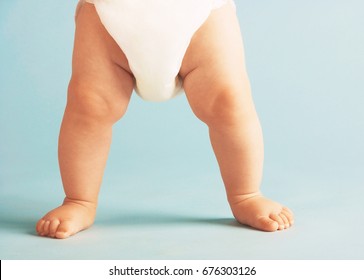 Low section of baby boy in diaper standing isolated on blue background