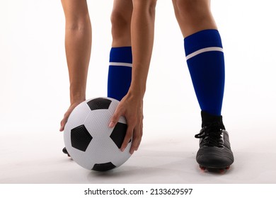 Low section of biracial female player holding soccer ball while standing against white background. white background, unaltered, sport, soccer shoe, sock, athlete and women's soccer. - Powered by Shutterstock