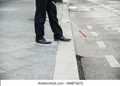 Low Section Of A Blind Person Crossing Street