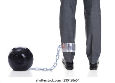 Low Section Of Businessman With Ball And Chain Attached To Leg Against White Background