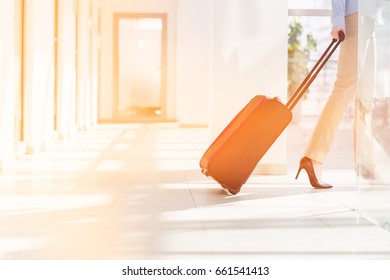 Low Section Of Businesswoman With Luggage Leaving Airport