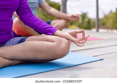 Low section of caucasian senior couple practicing meditation while doing yoga at tourist resort. Unaltered, love, together, retirement, vacation, beach, hand, mudra, fitness and active lifestyle. - Powered by Shutterstock