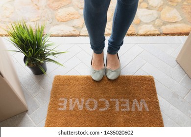 Low Section Of Caucasian Woman Standing Near Welcome Mat In Front Of Door At Home 