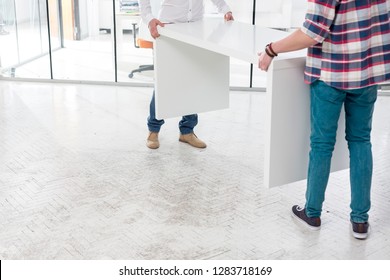 Low section of creative colleagues carrying desk while setting up office - Shutterstock ID 1283718169