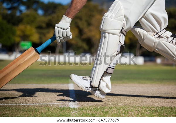 Low section of cricket player scoring run on field\
during sunny day