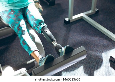 Low Section Of Disabled Active Senior Caucasian Woman With Leg Amputee Exercising With Leg Press Machine In Fitness Studio. Strong Active Senior Female Amputee Training And Working Out