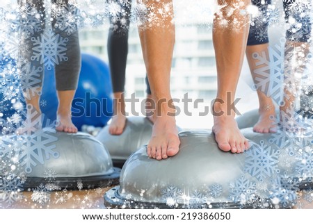 Low section of fit people standing on exercise equipment against snow