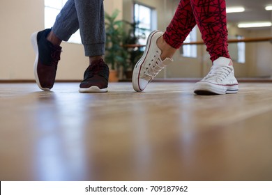 Low Section Of Friends Rehearsing Dance On Wooden Floor In Studio 