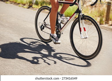 Low Section Image Of Woman Riding Bicycle On Country Road. Cropped Image Of Female Athlete Cycling. Action Shot Of A Racing Cyclist.