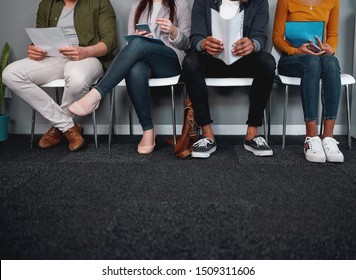 Low Section Of Job Applicants Waiting In Corridor Preparing For Recruiting Process - Photo Of Diverse Feet Sitting In A Row Waiting For Job Interview