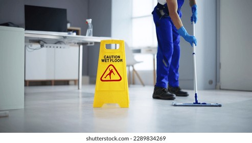 Low Section Of Male Janitor Cleaning Floor With Caution Wet Floor Sign In Office - Powered by Shutterstock