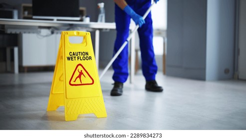 Low Section Of Male Janitor Cleaning Floor With Caution Wet Floor Sign In Office - Powered by Shutterstock