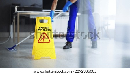 Low Section Of Male Janitor Cleaning Floor With Caution Wet Floor Sign In Office Foto d'archivio © 
