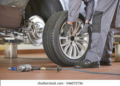 Low Section Of Male Mechanic Repairing Car's Tire In Repair Shop