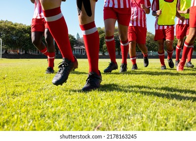 Low section of male multiracial players wearing red socks and black shoes running on grassy field. Playground, unaltered, soccer, sport, teamwork, competition, exercising, training and fitness. - Powered by Shutterstock