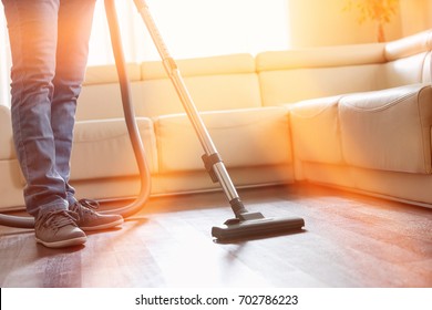 Low Section Of Man Cleaning Hardwood Floor With Vacuum Cleaner