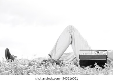 Low section of man lying by vintage radio on grass against clear sky