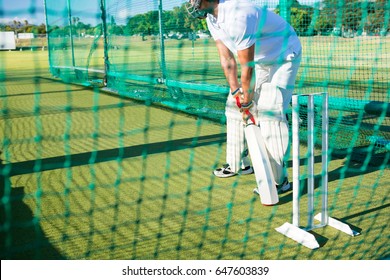 Low section of man playing cricket at field on sunny day