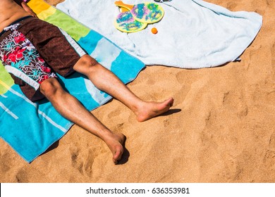 Low Section Of A Man Relaxing On A Colorful Beach Towel