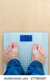 Low Section Of Man Standing On Weight Scale