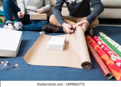 Low section of man and woman wrapping gift boxes at home during Christmas time - Powered by Shutterstock