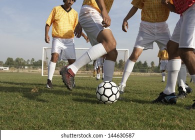Low section of men playing soccer on the field