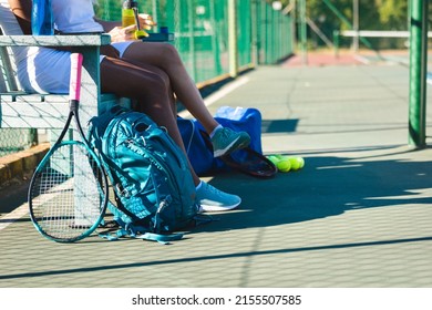 Low Section Of Multiracial Female Players Sitting On Bench At Tennis Court During Break On Sunny Day. Unaltered, Sport, Competition And Tennis Game Concept.