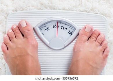 Low Section Of Overweight Obese Person Measuring Body Weight On Weighing Scale