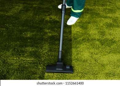 Low Section Of Person Cleaning Green Carpet With Vacuum Cleaner 