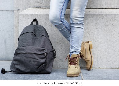 Low section portrait of backpack on sidewalk with female standing by