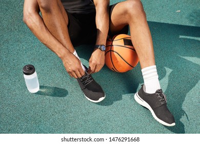 Low section portrait of contemporary African-American man tying sports shoes in basketball court outdoors, copy space background - Powered by Shutterstock