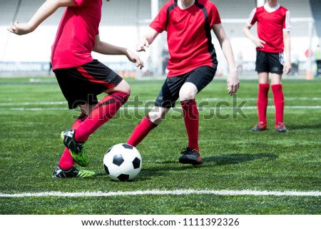 Low section portrait of two teenage boys playing football during practice of junior team in stadium, copy space