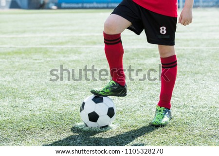 Low section portrait of unrecognizable teenage boy standing on football field and stepping on ball, copy space