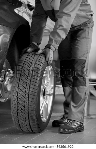 Low\
section of repairman fixing car\'s tire in\
workshop