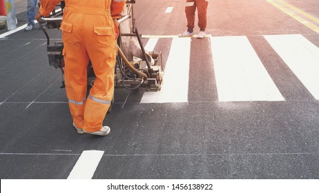 Low Section Of Road Workers Using Thermoplastic Spray Road Marking Machine To Painting Pedestrian Crosswalk On Asphalt Road Surface In The City 