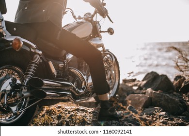 low section view of biker sitting on classical motorbike outdoors