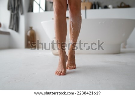 Low section view of female wet foamy feet on bathroom floor