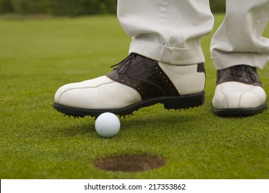 Low Section View Of A Man Putting A Golf Ball Into A Hole With A Foot