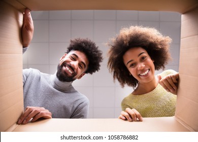 Low Section View Of A Young Happy Couple Looking Inside Cardboard Box