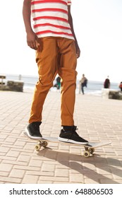 Low section view of young man skateboarding outside on promenade by the beach