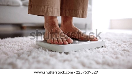 Low Section Of Woman Standing On Weight Scale